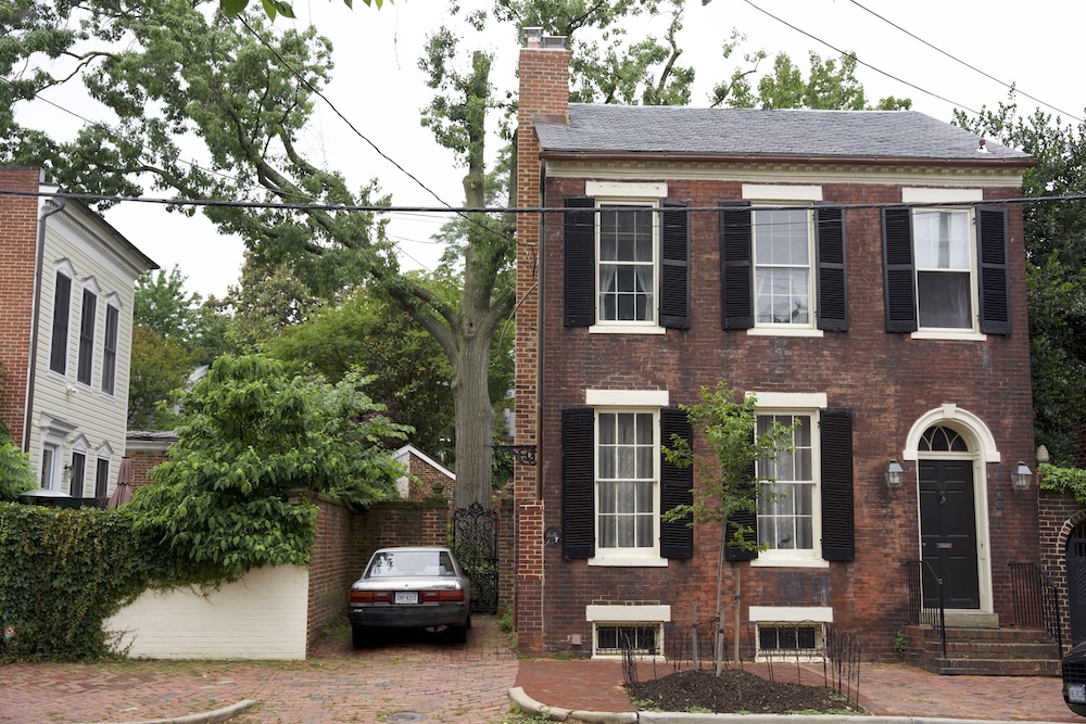 A brick Old Town townhouse with black shutters and a narrow side driveway.